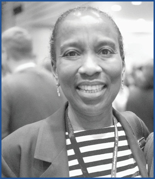 Black and white photo of a woman wearing earrings and a striped shirt, with her hair pulled back.